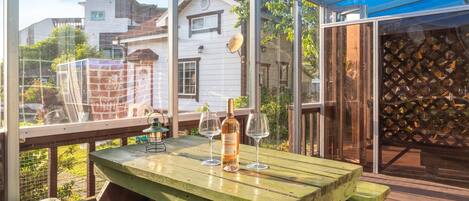 Una terraza de madera con una mesa, dos copas de vino y una botella.
