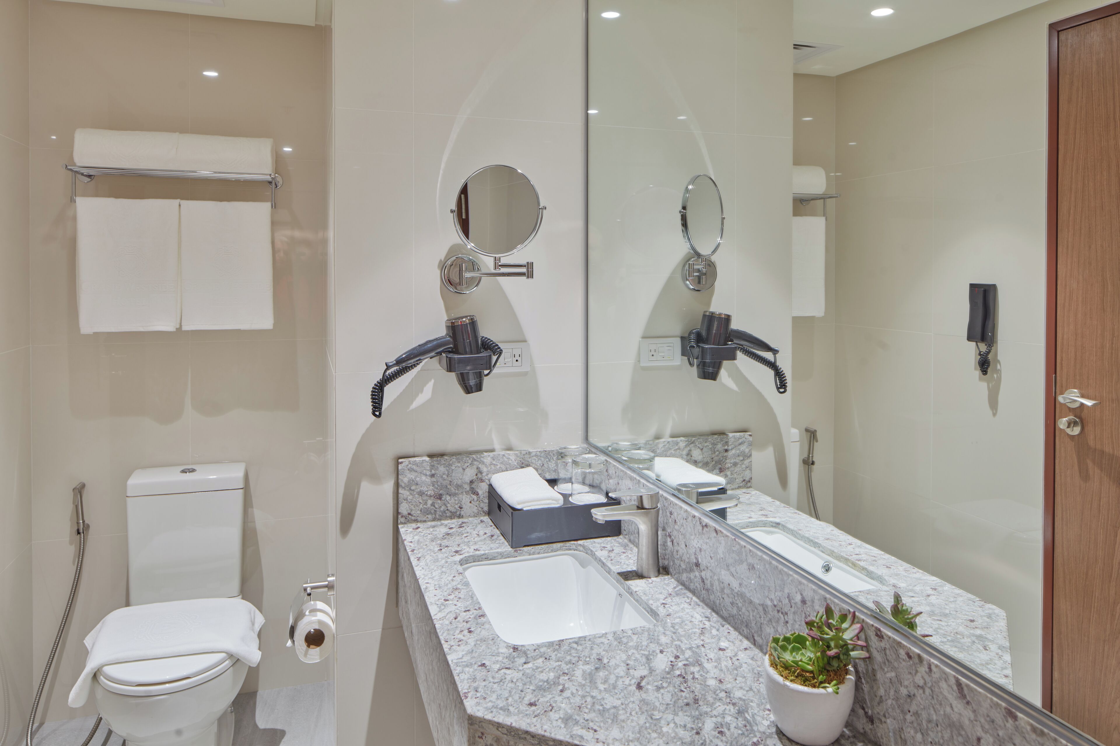 A modern bathroom with a marble sink, a large mirror, a toilet, and a shower.