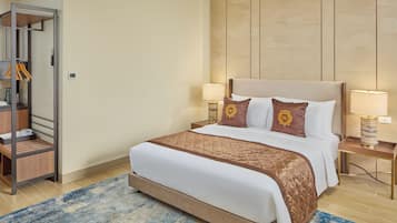 A neatly arranged hotel room with a bed, bedside lamps, a nightstand, a wooden wardrobe, and a blue patterned rug.
