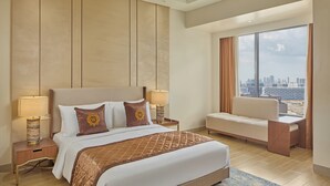 Una habitación de hotel moderna con una cama grande, un área de descanso y vistas a la ciudad.