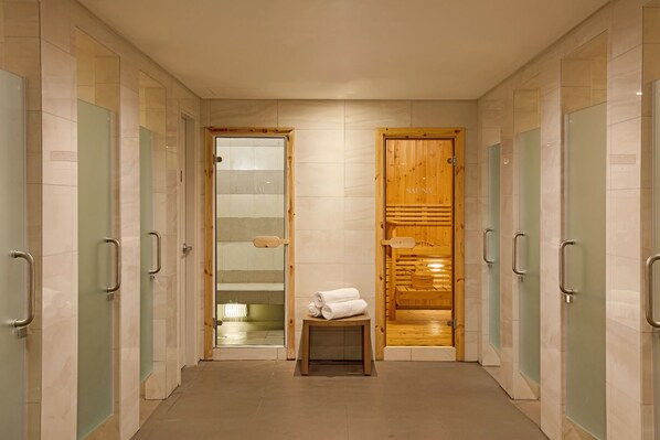 A hallway with multiple sauna doors, a wooden sauna door, and a small table with towels.