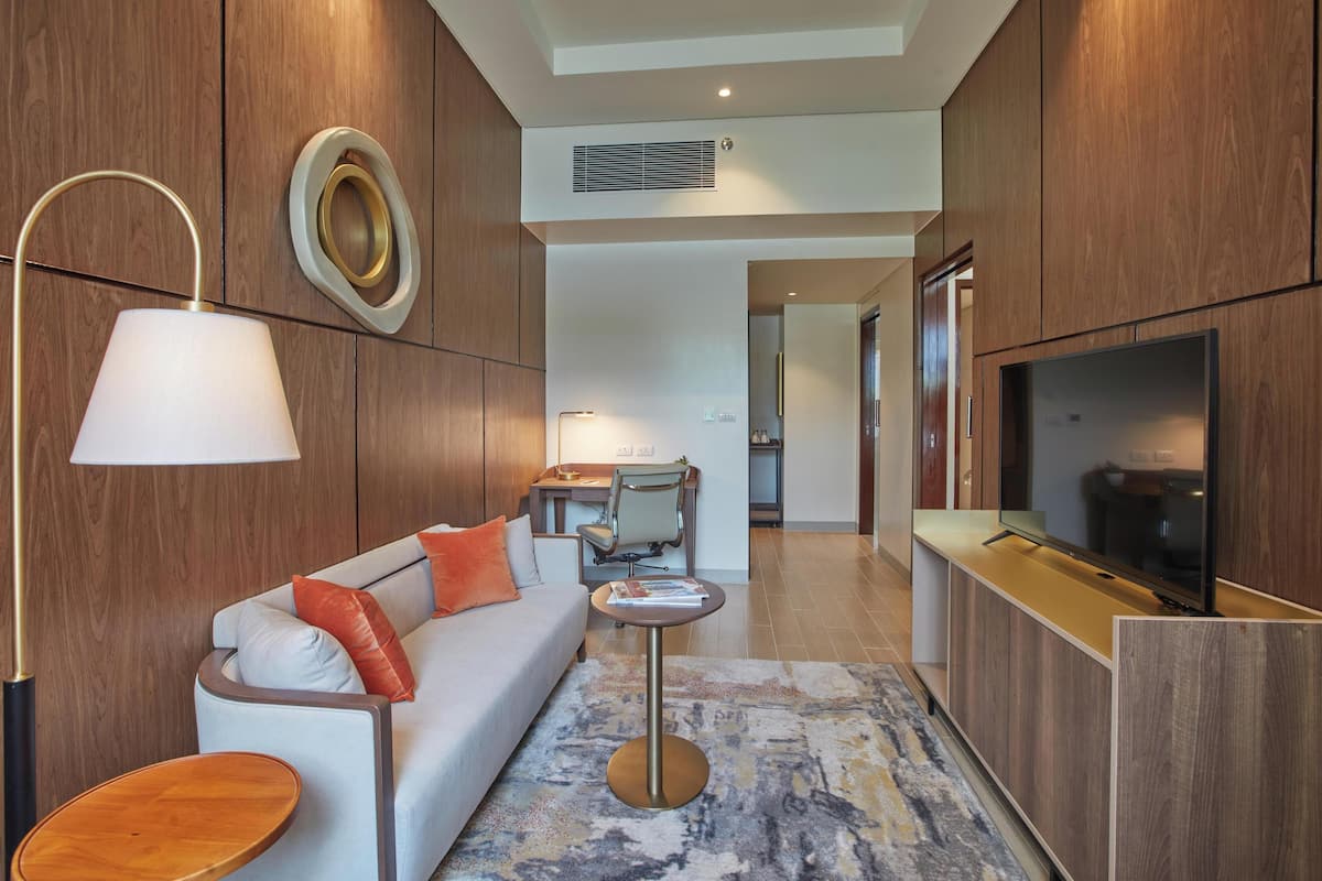 A modern living room with a sofa, a coffee table, a TV, and a desk with a chair.
