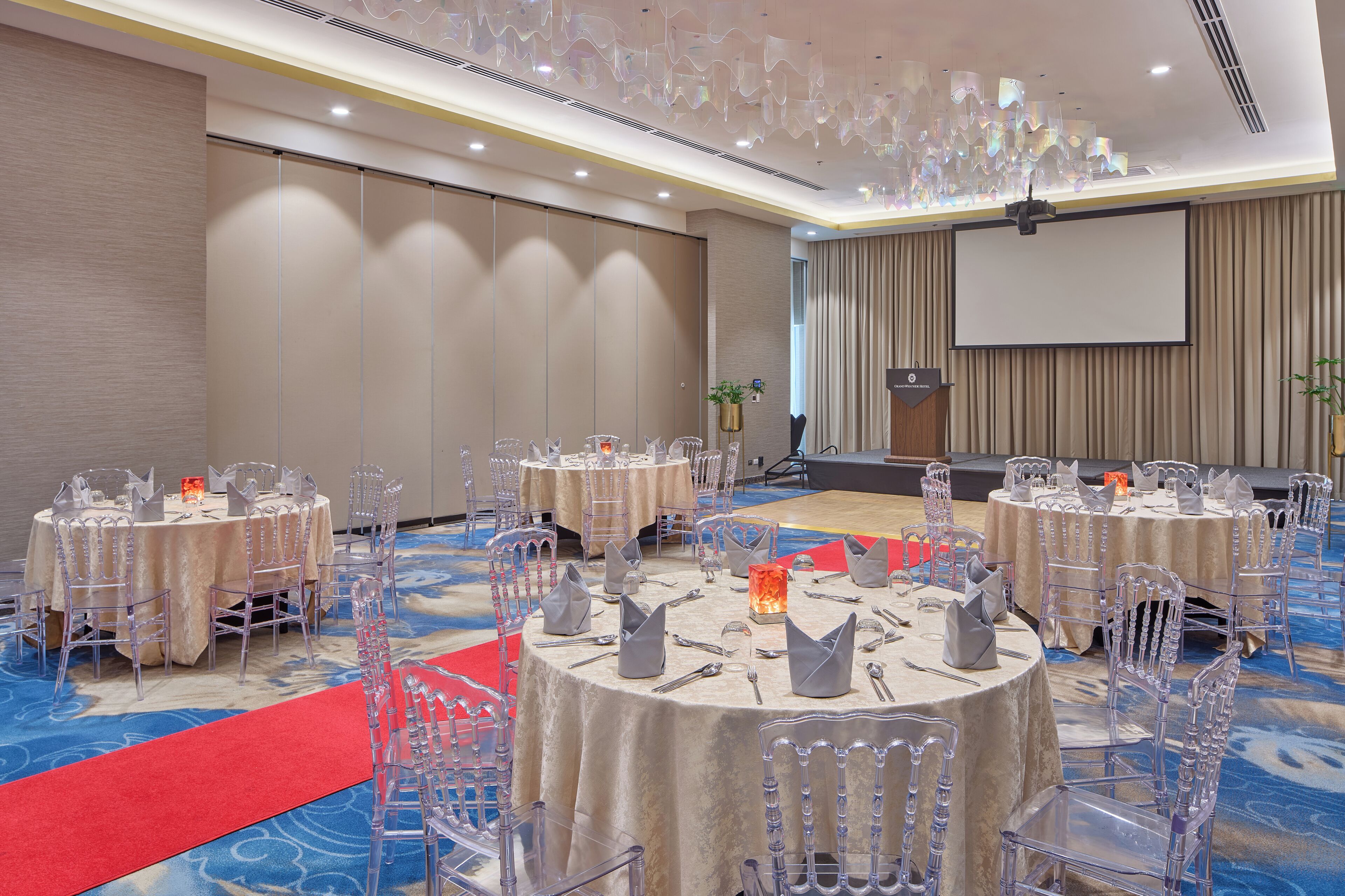 A conference room with round tables, clear chairs, and a red carpet.