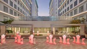 Un patio de hotel con arquitectura moderna, varias zonas de estar y un espacio central abierto.