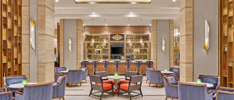 A bar area with multiple seating arrangements, a television, and a bar counter with various bottles.