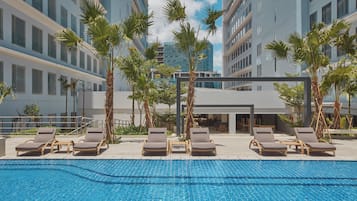 Relax by the pool surrounded by palm trees and contemporary hotel buildings.