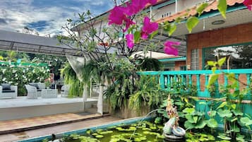 A courtyard with a fountain, lush greenery, and a decorative statue.