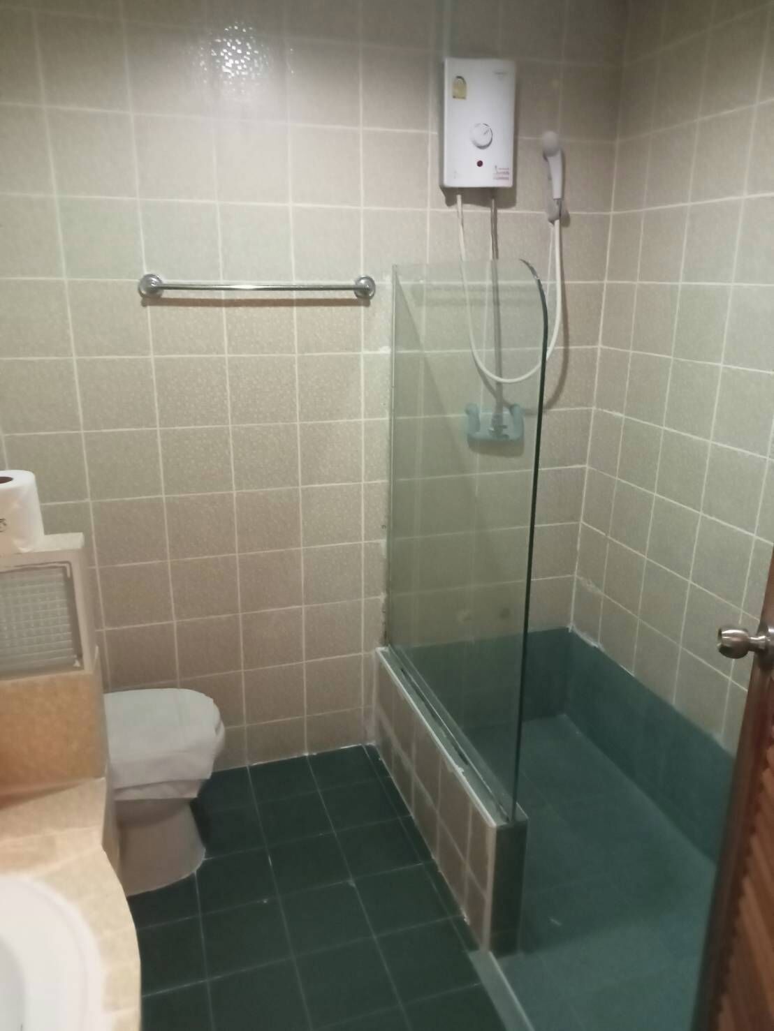 Un baño pequeño con inodoro, cabina de ducha de vidrio y secamanos.