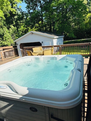 A hot tub on a wooden deck with a shed in the background.