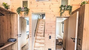 Un intérieur en bois avec un escalier central, des murs en bois et un climatiseur fixé au plafond.