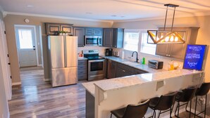 A modern kitchen with stainless steel appliances, a marble countertop, and bar stools. -  Cozy country home with a beautiful creek at the back of the property.  (Mulberry)