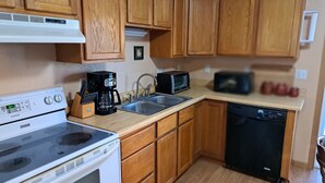 A kitchen with wooden cabinets, a stove, a microwave, and a dishwasher. - River Road Getaway (Muscoda)