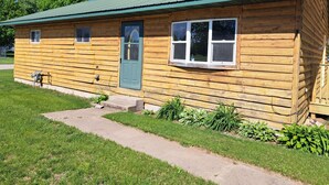 A wooden cabin with a green door, a small porch, and a window. - River Road Getaway (Muscoda)