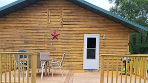 A wooden cabin with a deck, a door, and a star decoration. - River Road Getaway (Muscoda)