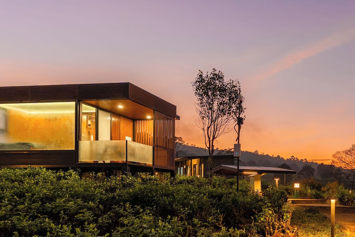 Una casa moderna con un amplio ventanal, un balcón y vistas del paisaje circundante.