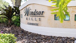 A sign for Windsor Hills Clubhouse surrounded by trees and foliage.