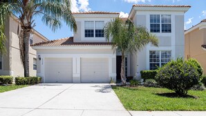 A two-story house with a garage, a well-maintained lawn, and a palm tree.