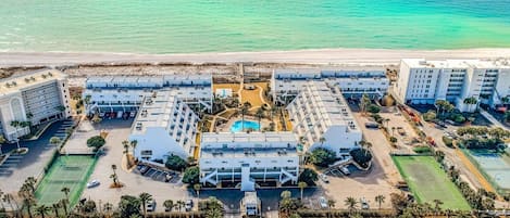 A coastal hotel with multiple buildings, a central pool, and a beach view.