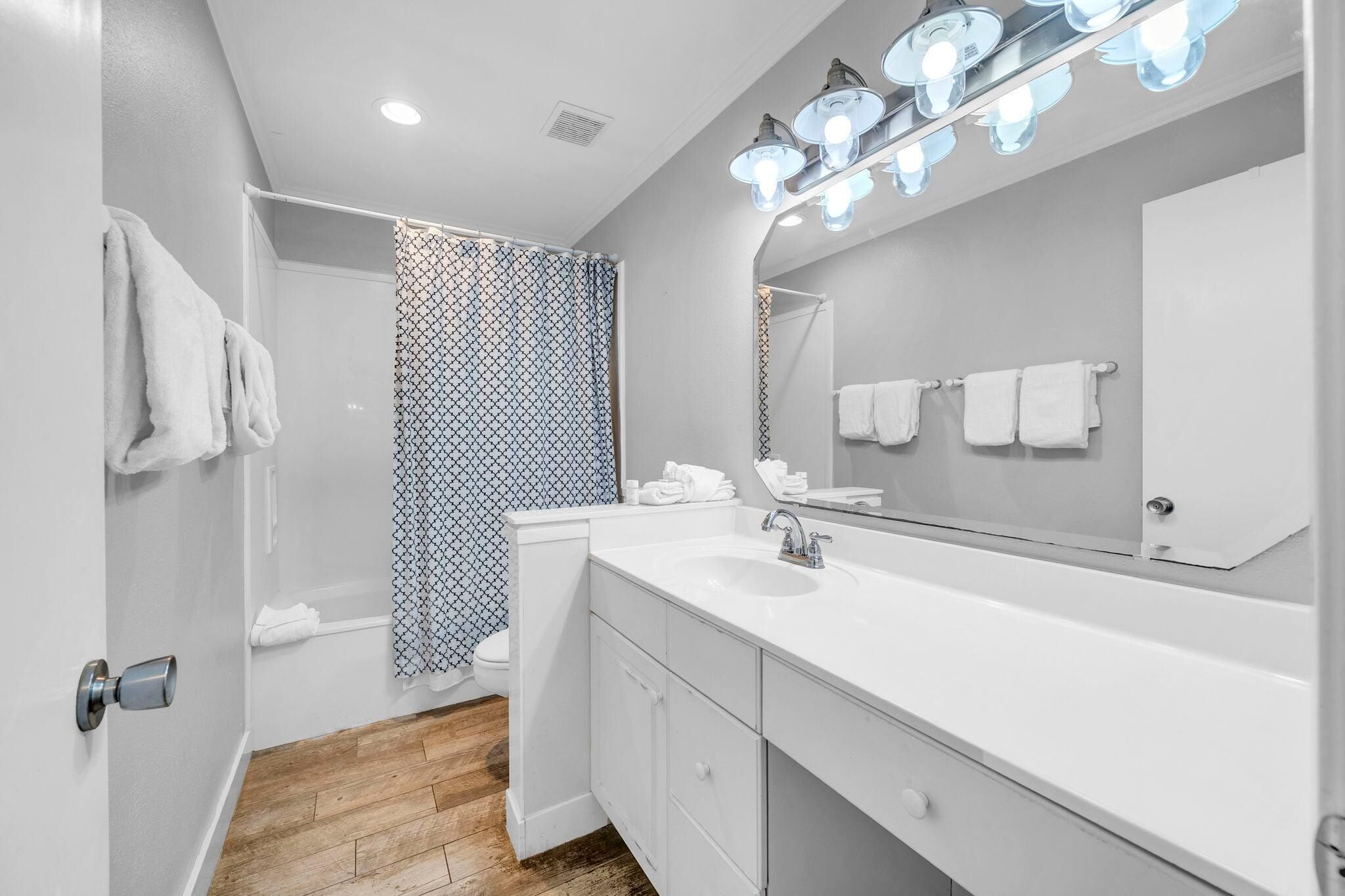 Une salle de bain moderne avec un lavabo blanc, un miroir et un rideau de douche.