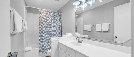 Une salle de bain moderne avec un lavabo blanc, un miroir et un rideau de douche.