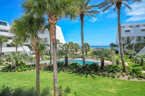 A resort with palm trees, a pool, and a view of the ocean. - Aegean 210 (Destin)