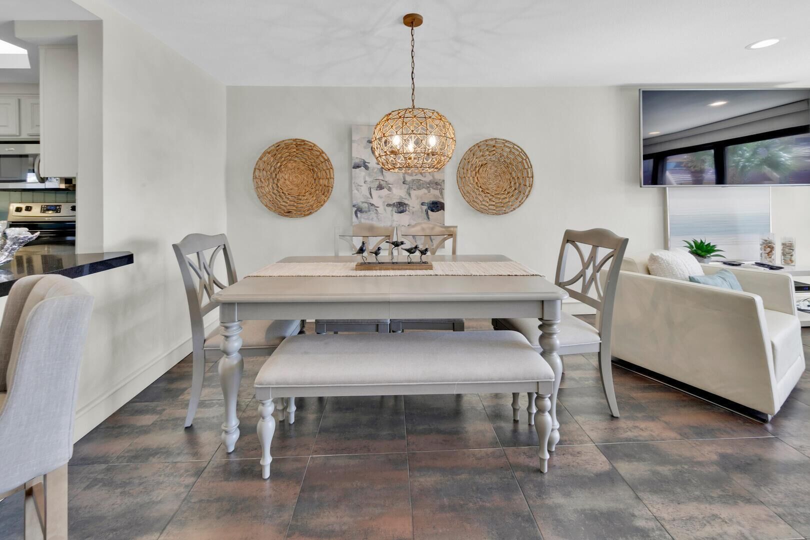A dining area with a large table, chairs, and a hanging light fixture.