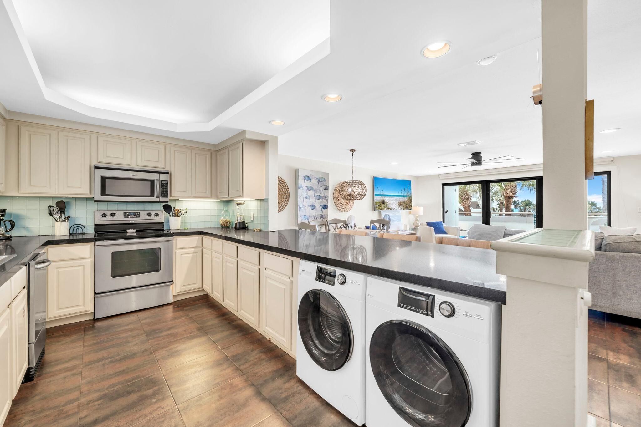 A modern kitchen with built-in appliances, a central island, and a view of the living area.