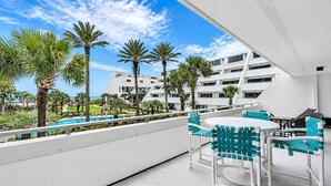 A rooftop terrace with outdoor seating, palm trees, and a pool. - Aegean 211 (Destin)