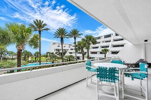 Une terrasse sur le toit avec des espaces de détente en plein air, des palmiers et une piscine.