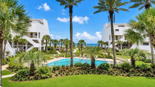 A resort with a pool, palm trees, and a clear view of the ocean. - Aegean 211 (Destin)