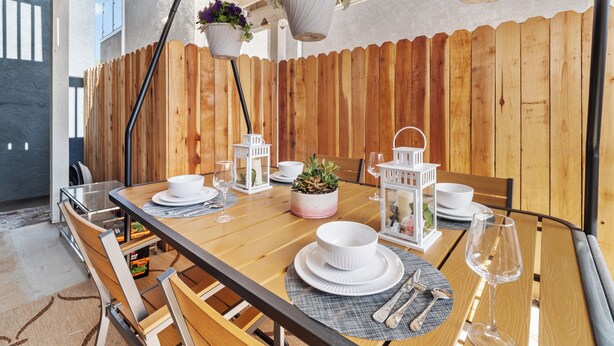 A wooden dining table set with white plates, bowls, and cutlery, surrounded by wooden chairs. - Super Spacious Family Vacation Home! (San Diego)