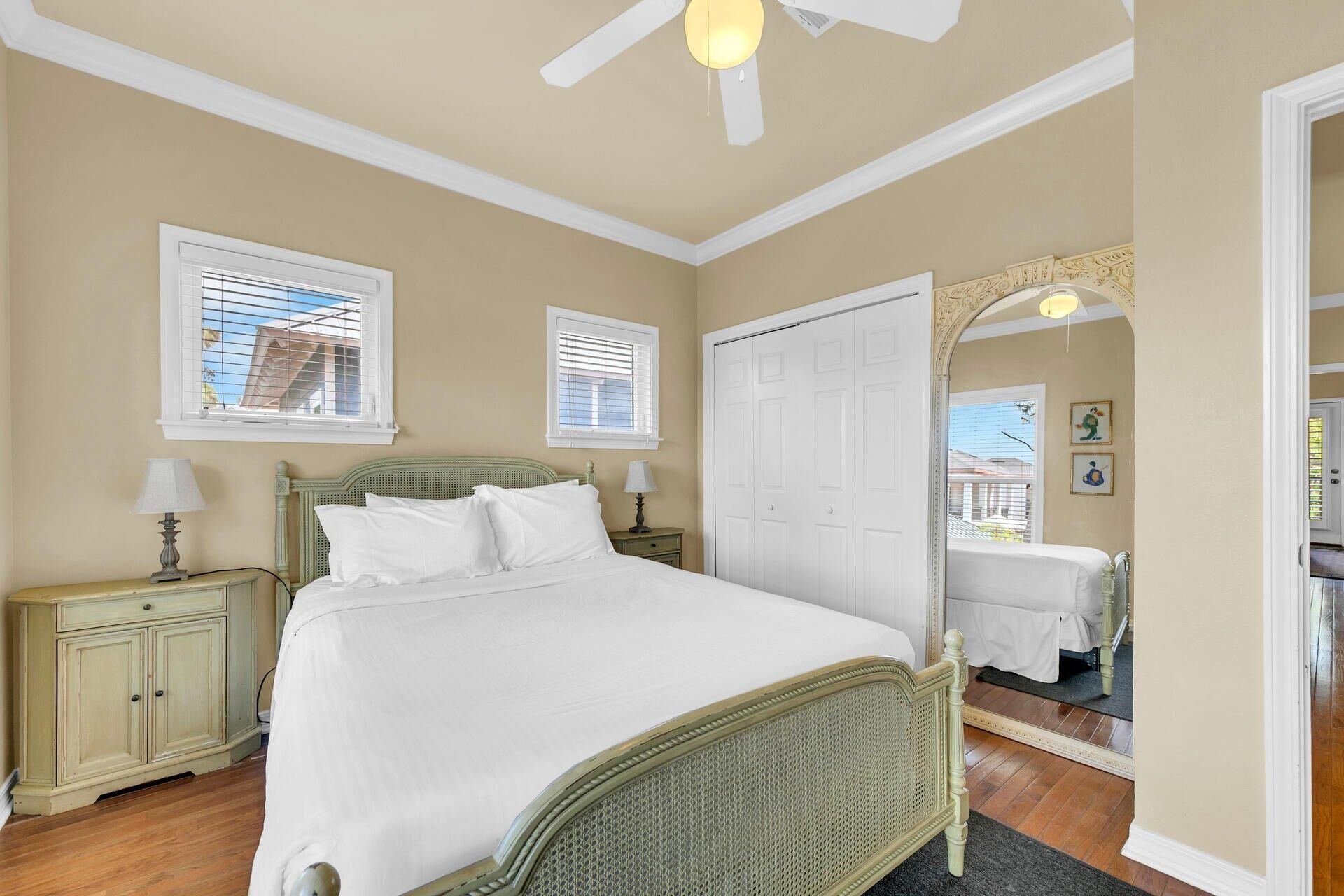 A bedroom with a bed, two bedside tables, a wardrobe, and a ceiling fan.
