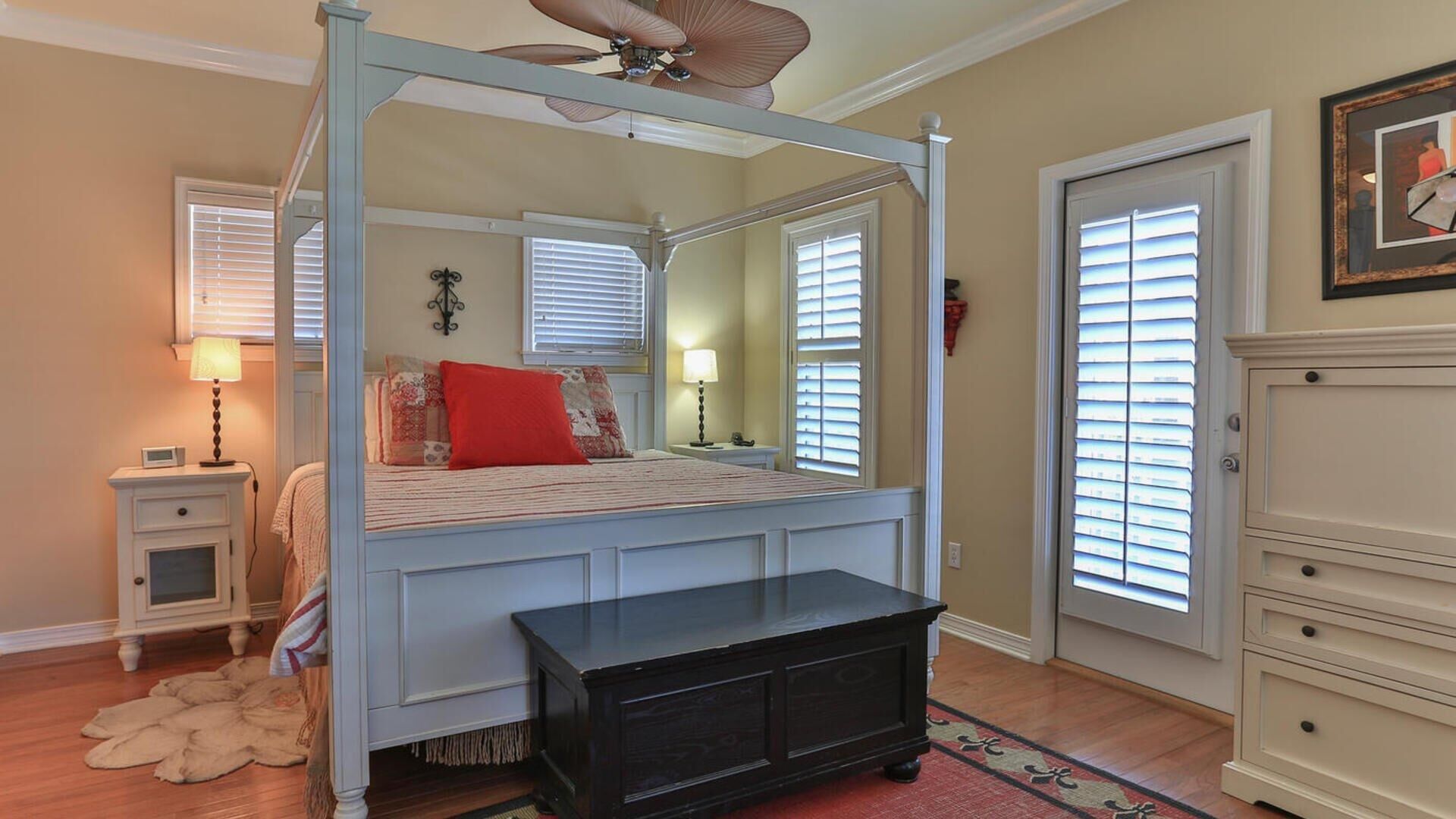 A four-poster canopy bed with a wooden bench, bedside tables, and a dresser.