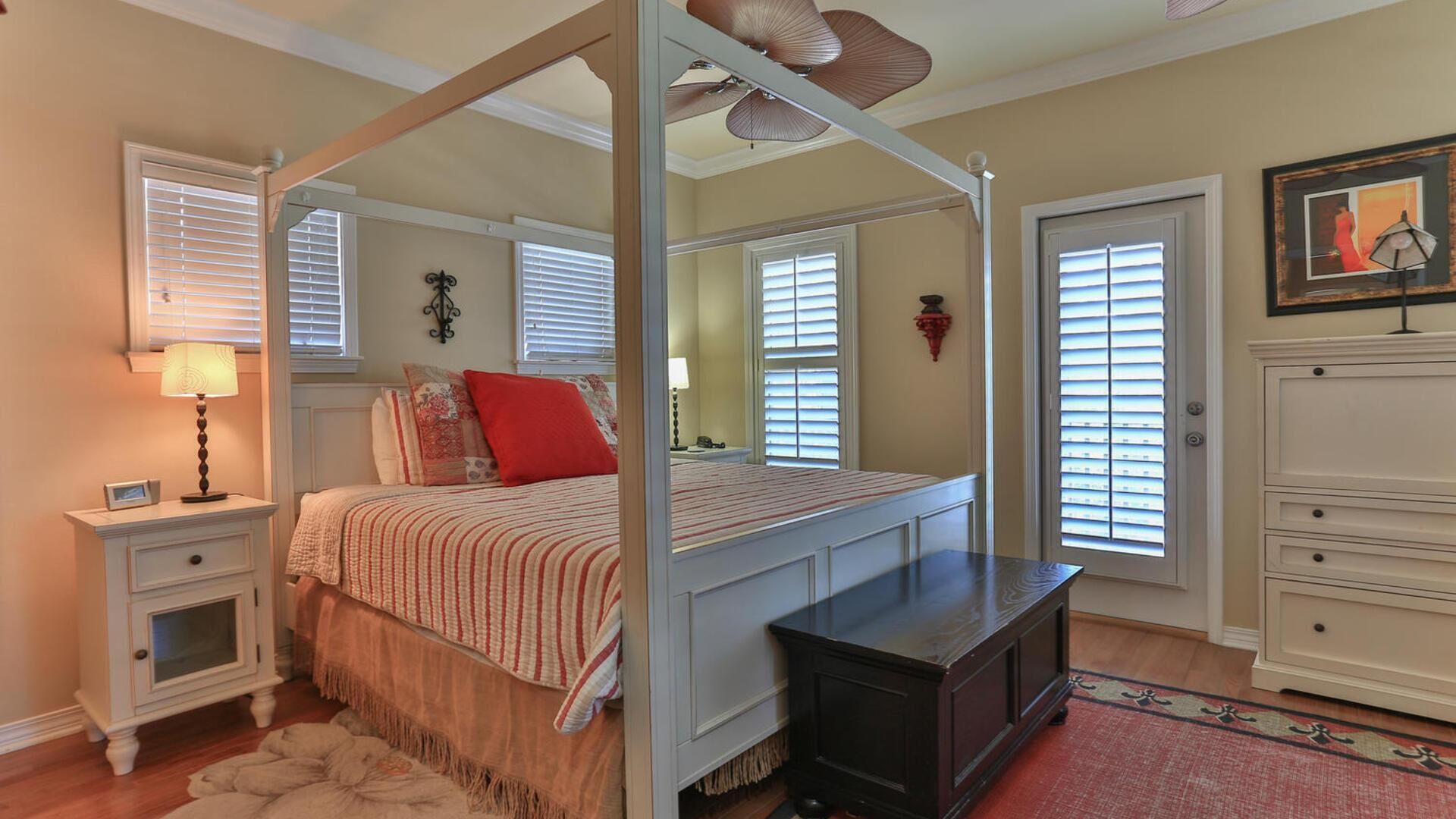 A four-poster bed with a canopy, bedside tables, a dresser, and a mirror.