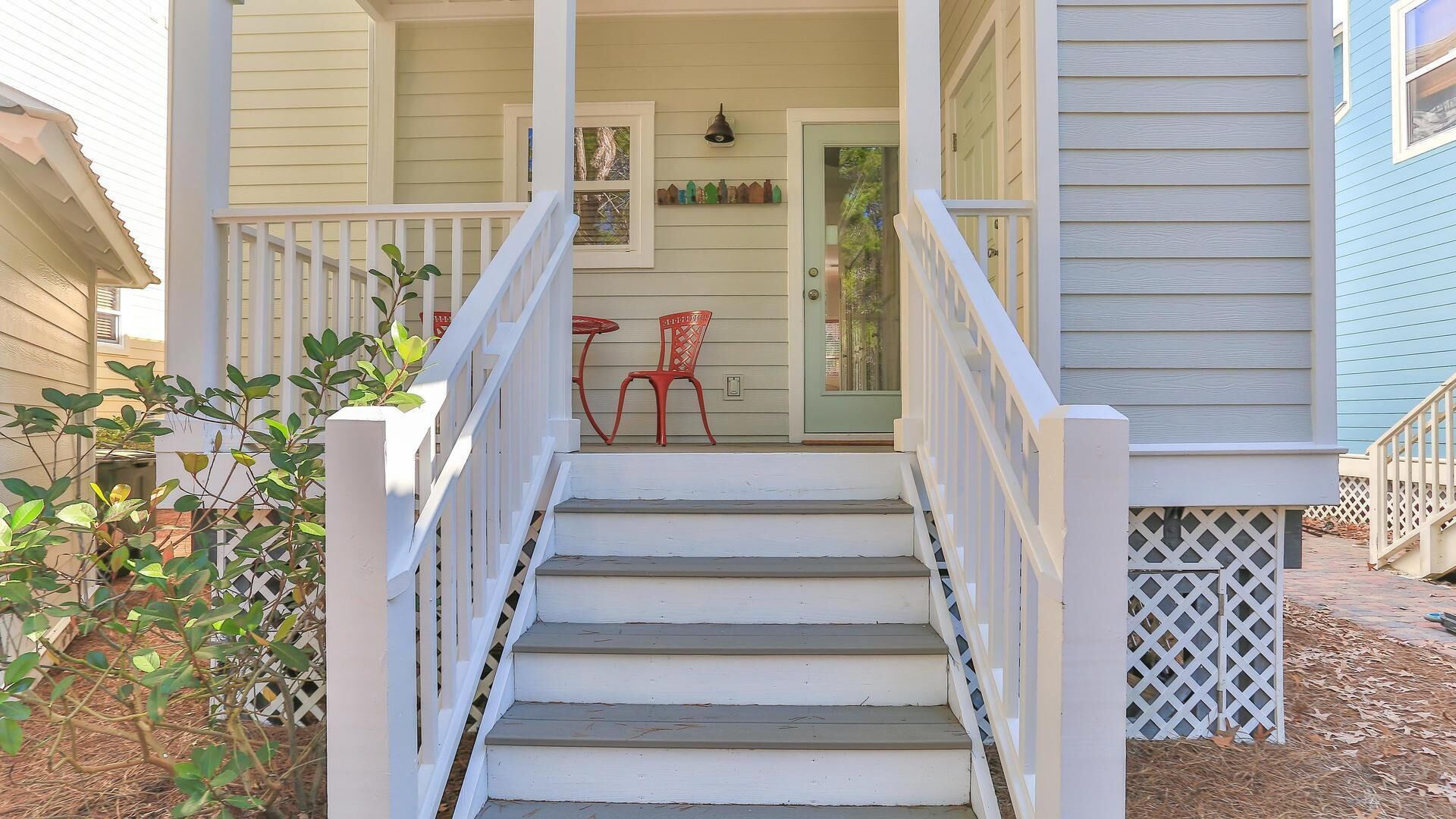 A front porch with a set of stairs leading to a door, a small table, and a chair.