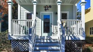 A porch with a blue door, white railings, and a cartoon character decoration. - Monkey Business (Santa Rosa Beach)