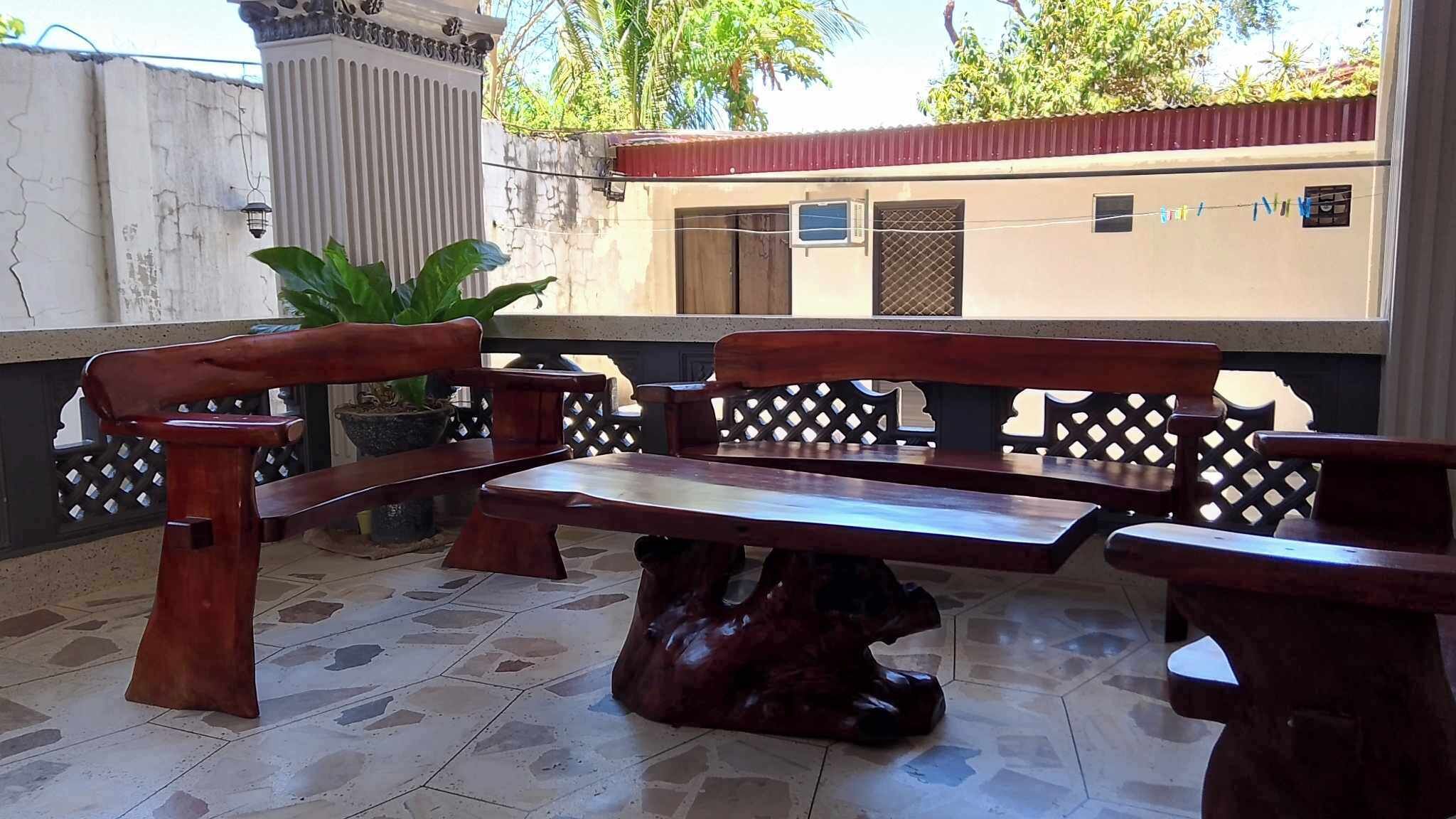 A patio area with a wooden bench and table, surrounded by a decorative fence.