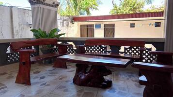 A patio area with a wooden bench and table, surrounded by a decorative fence.