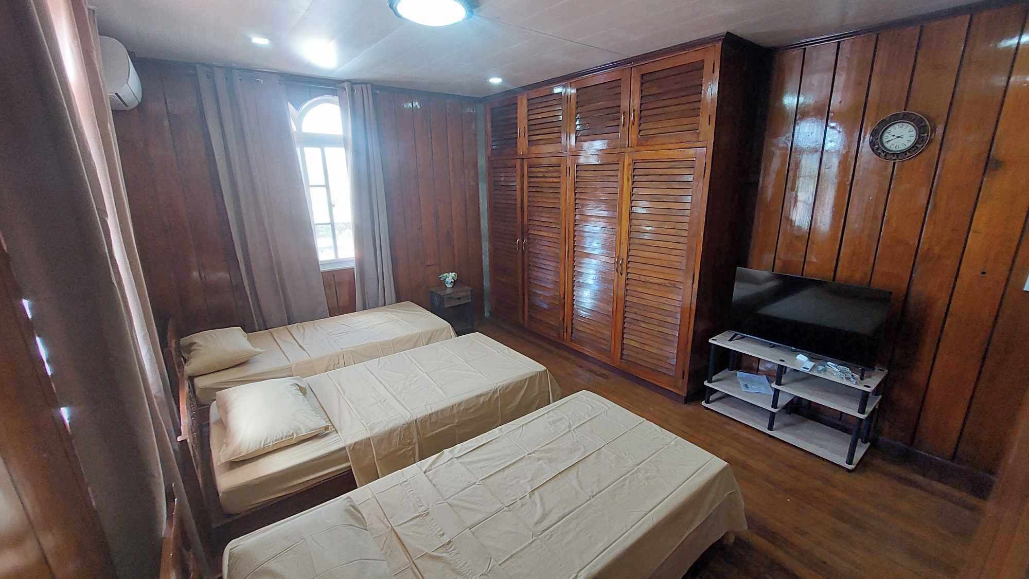 A room with two beds, a TV, and wooden paneling.