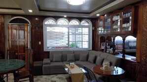 Cómoda sala de estar con un sofá seccional, una mesa de comedor con superficie de vidrio y un mueble de madera con puertas de cristal.