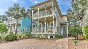 A multi-story building with a balcony, surrounded by palm trees and a brick pathway. - Robbins' Nest (Santa Rosa Beach)