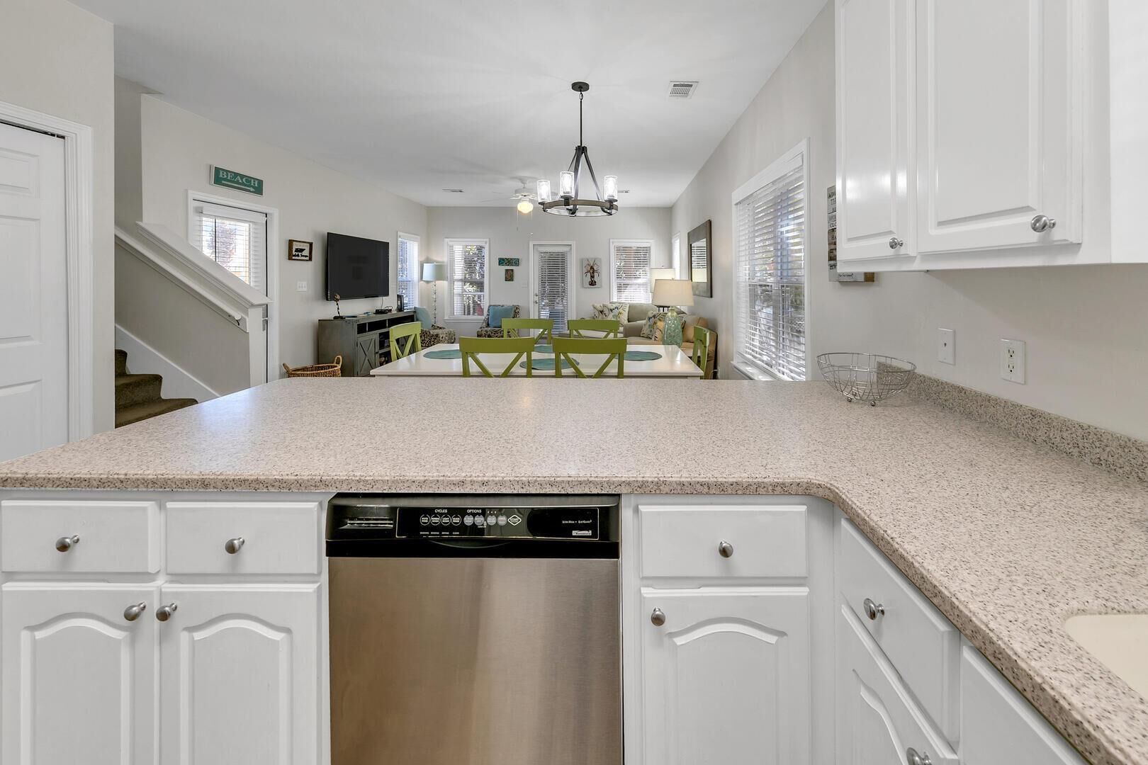 A kitchen with white cabinets, a dishwasher, and a dining area with a table and chairs.