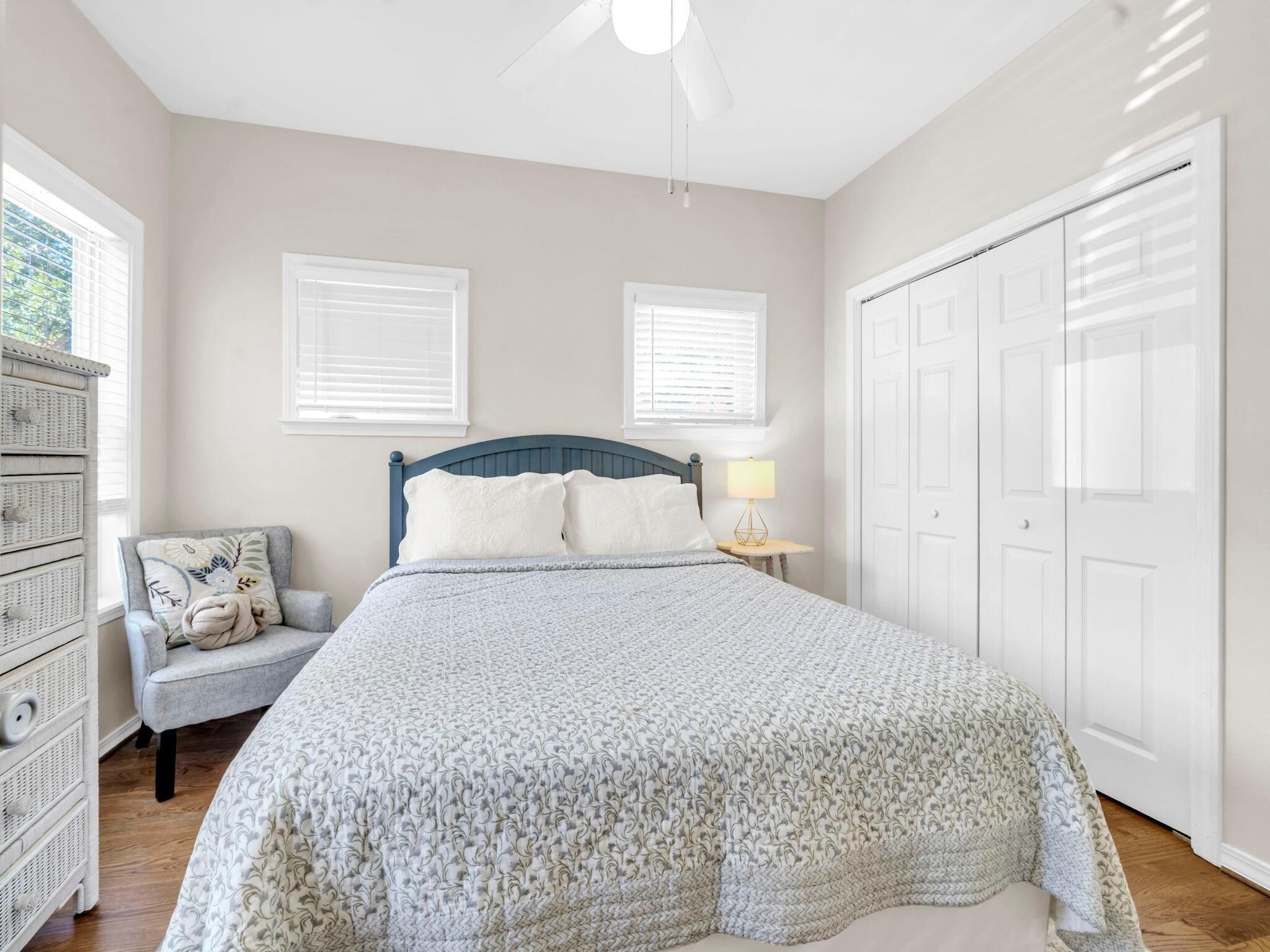 A bedroom with a bed, a chair, a dresser, and a closet.