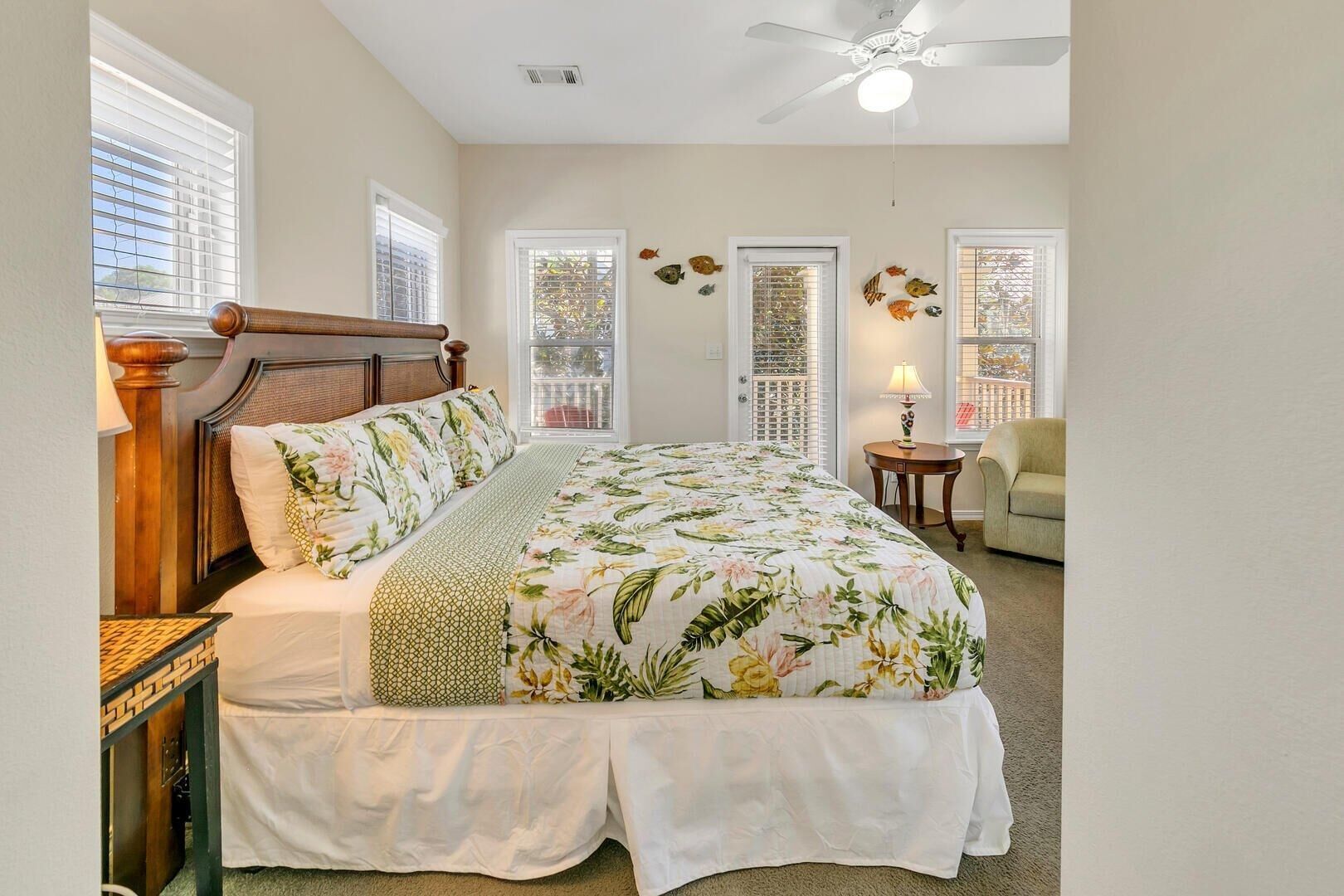 A bedroom with a large bed, a ceiling fan, and two windows with decorative shutters.