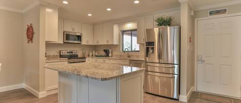 Una cocina moderna con armarios blancos, electrodomésticos de acero inoxidable y encimera de granito.