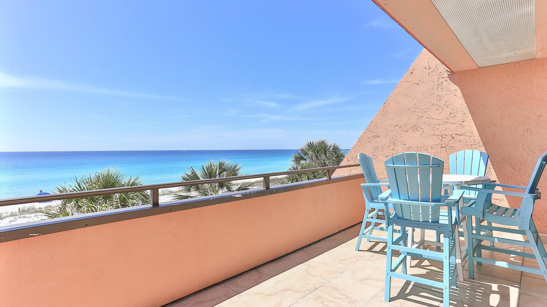 A balcony with a view of the ocean, featuring a table and chairs.