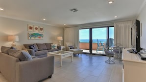 Un salon spacieux avec un balcon donnant sur la mer, aménagé avec un canapé, une table basse et des fauteuils.