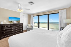 Une chambre d’hôtel avec un grand lit, une commode, une télévision et un balcon donnant sur l’océan.