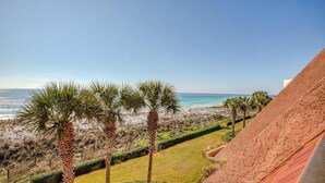 A beachfront view with palm trees, a sandy beach, and a clear blue sky. - Aegean 309 (Destin)