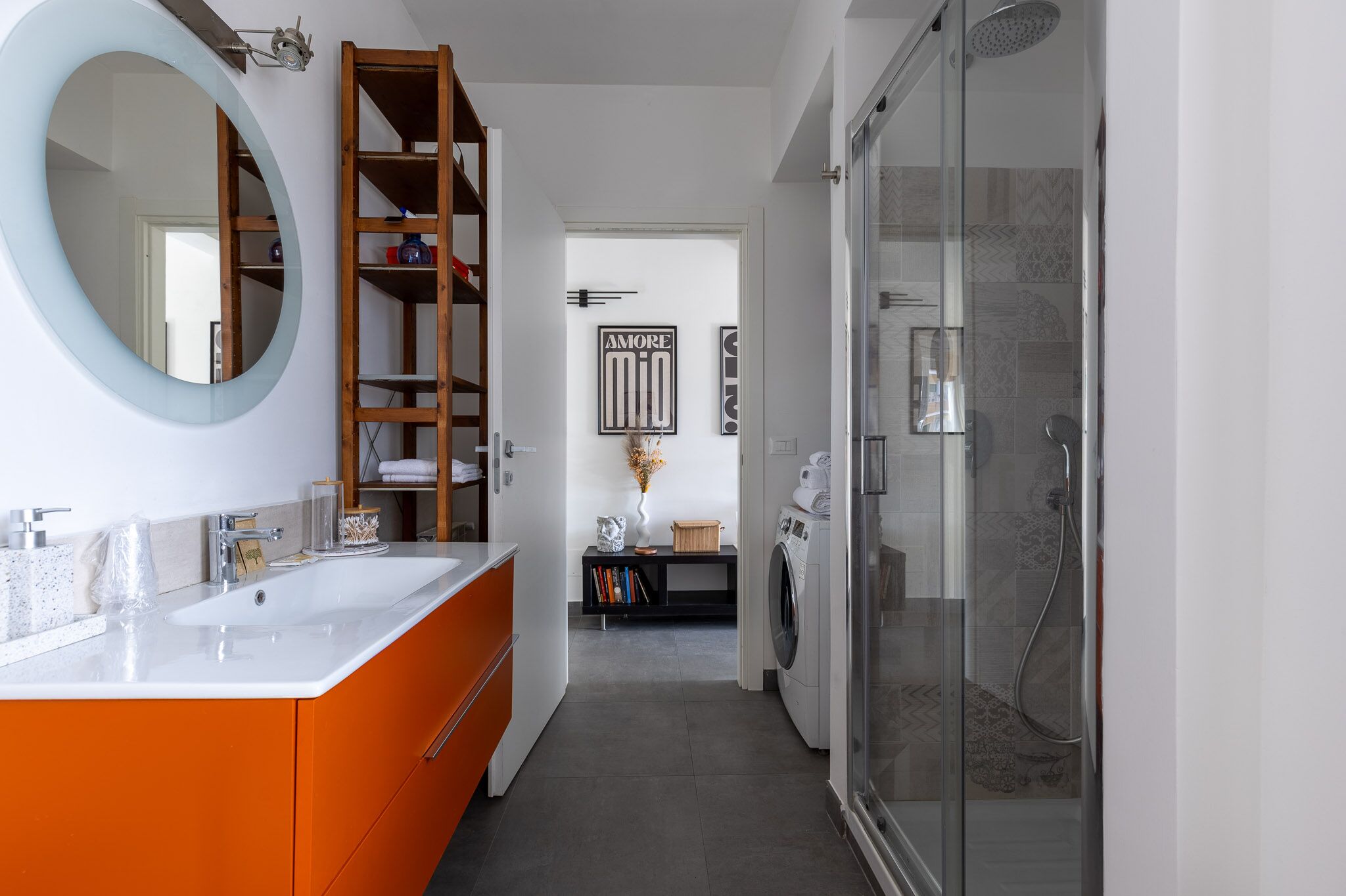 A modern bathroom with a large mirror, a glass-enclosed shower, and a built-in washing machine.